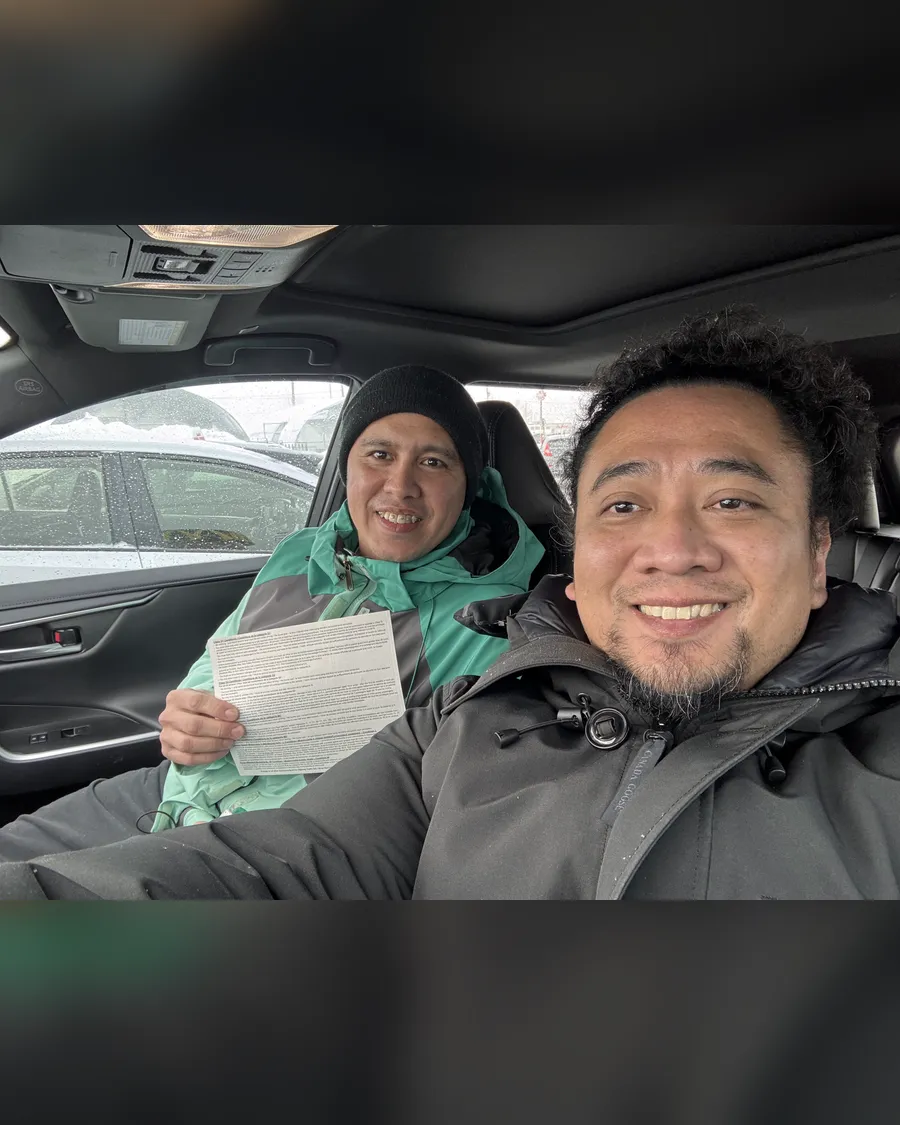 Student and instructor Allan inside the car, holding a road test result
