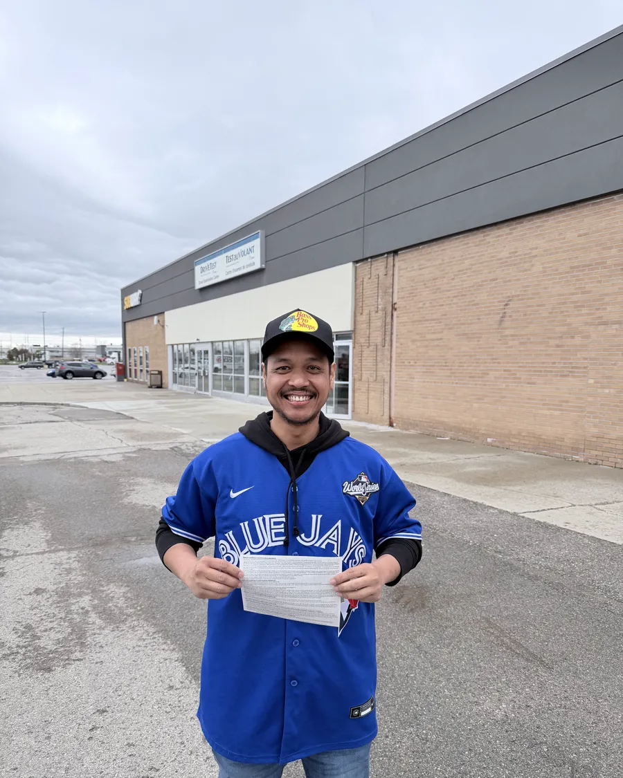 Student in a Blue Jays jersey outside the DriveTest centre, holding their road test result