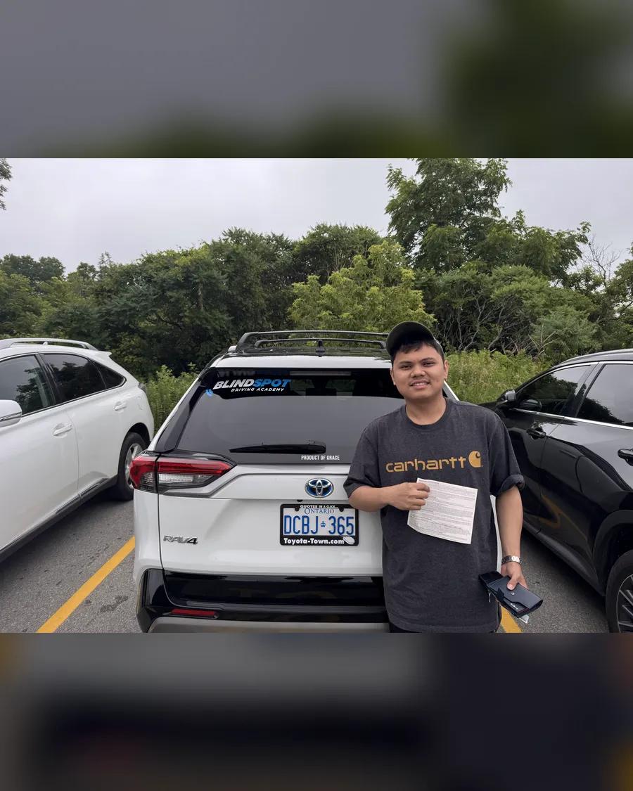 Student beside the Blindspot Driving Academy car, holding their road test result