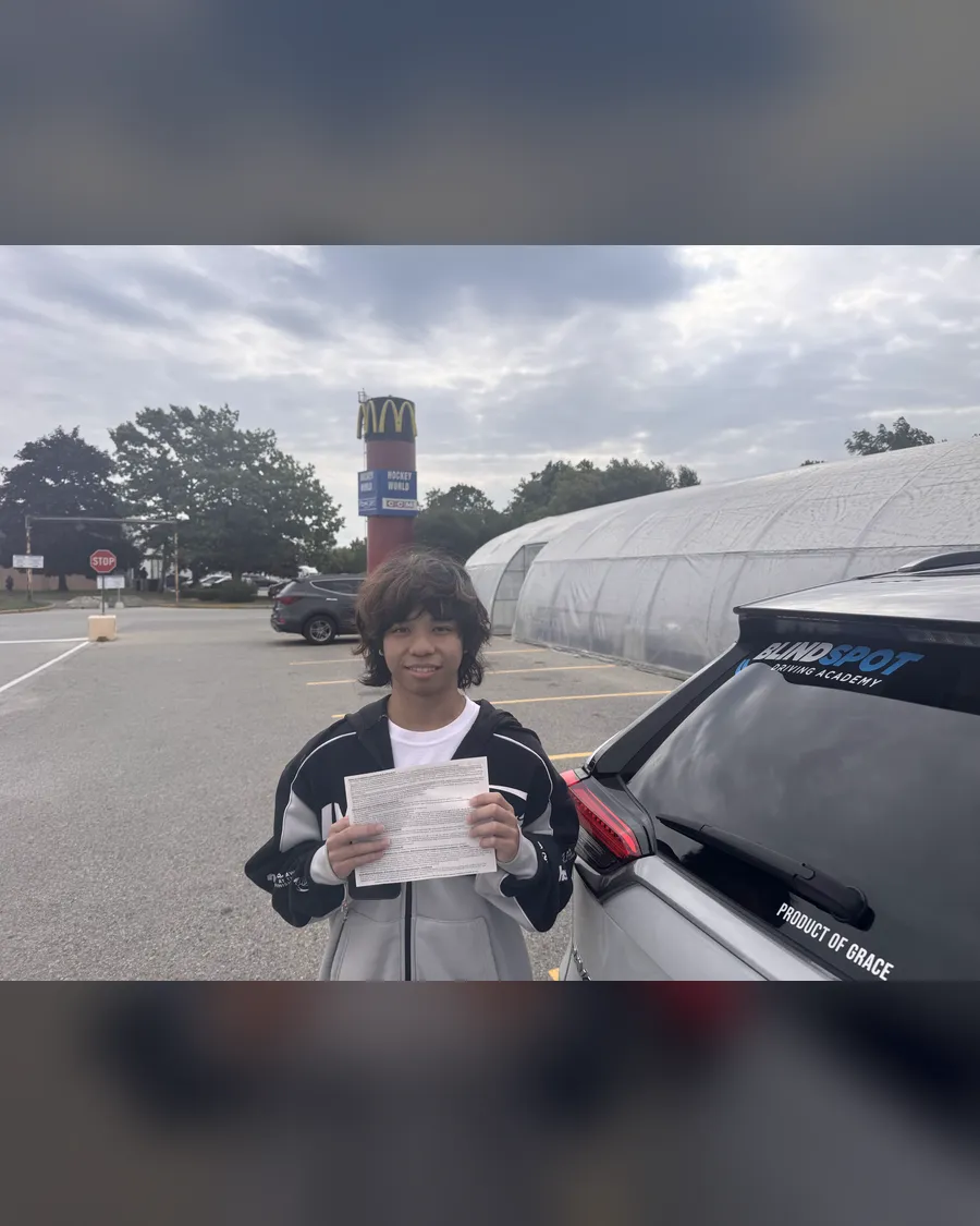 Student beside the Blindspot Driving Academy car, holding their road test result