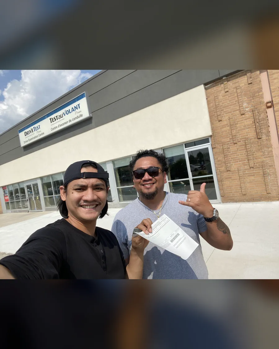 Two students outside the DriveTest centre, holding a road test result